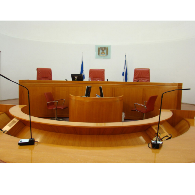 אולם בית המשפט בצבע חום עם 3 כסאות לשופטים ועמדה לעדים באמצע